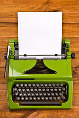 green typewriter on wooden ground with copyspace