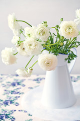 White Ranunculus in a flower vase on a table.