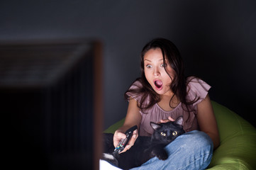 Woman swapping TV channels cat lying with her - Powered by Adobe