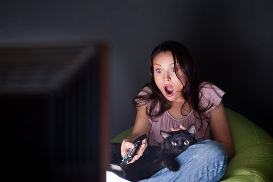 Woman Swapping TV Channels Cat Lying With Her