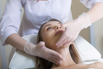 Fototapeta na wymiar Beautiful young woman receiving facial massage with closed eyes