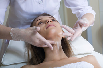 Beautiful young woman receiving facial massage with closed eyes