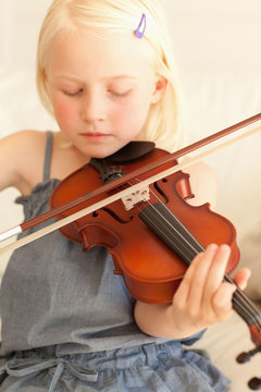 Sweet young girl softly plays the violin