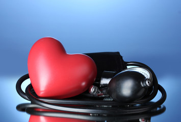 Black tonometer and heart on blue background