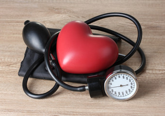 Black tonometer and heart on wooden background
