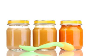 Jars of baby puree and spoon isolated on white