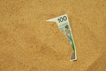 Banknot wystający z piasku