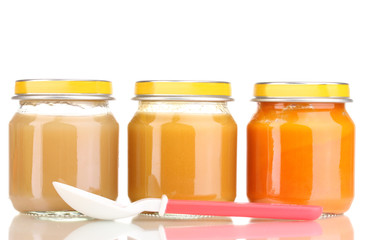Jars of baby puree and spoon isolated on white