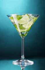 glass of cocktail with lime and mint on blue background
