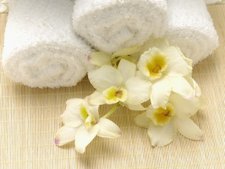 Obraz na płótnie Canvas oddział różowa orchidea i ręczniki rolkowe na matę