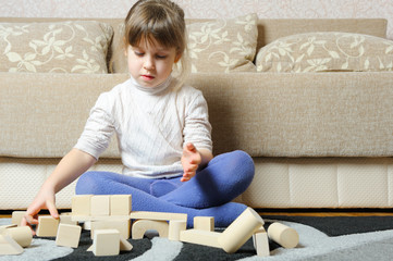 The little girl plays wooden toy cubes