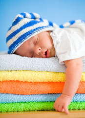 Sleeping baby on colorful towels stack