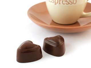 Chocolate candies and a cup of coffee on white background