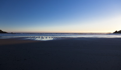 Fototapeta na wymiar late afternoon sun reflects on the water on an oregon beach