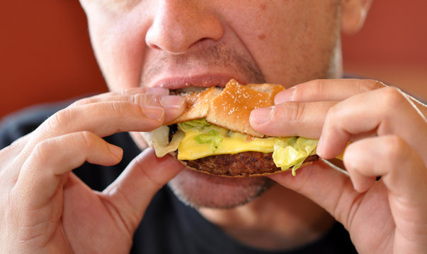 malbouffe homme mangeant un hamburger