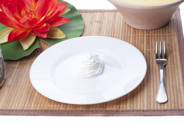 Shaped cream rose in a dish on straw mat