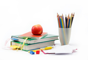 School supplies: books, notebook, pens, pencils, an apple on a w