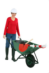 Woman pushing a wheelbarrow containing her tools