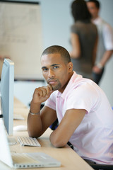 Naklejka premium Casual worker thinking whilst sat at computer