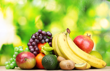 Assortment of exotic fruits on wooden table on green background
