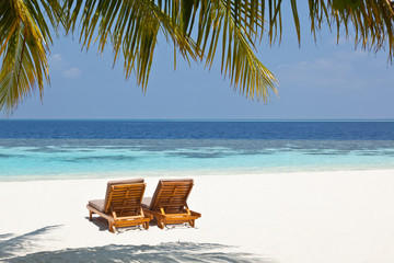 Two sun loungers on a deserted beach