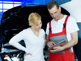 Mechanic and customer in a garage working with touchpad