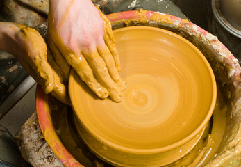 hands of a potter, creating an earthen jar of white clay