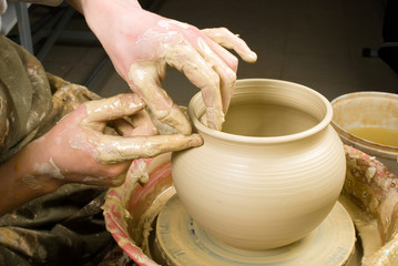 hands of a potter, creating an earthen jar of white clay