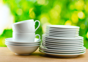 Clean dishes on wooden table on green background