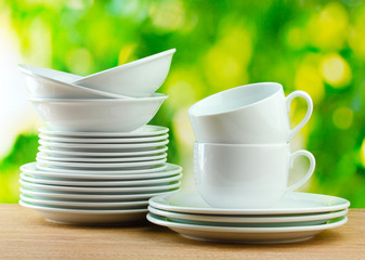 Clean dishes on wooden table on green background