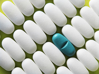 Rows of white pills and one blue in the middle