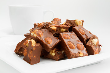 broken chocolate pieces with nuts on white plate