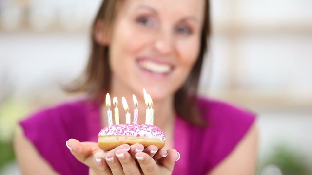gl&uuml;ckliche frau pustet geburtstagskerzen aus