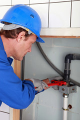Plumbing tightening a nut with a wrench