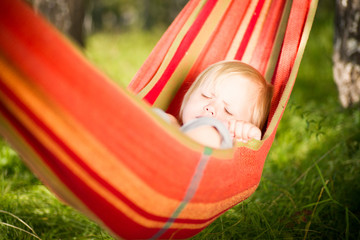Adorable baby lie in hammock resting under trees