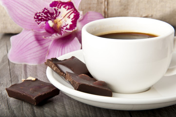 cup of coffee, chocolate and orchid on wooden background