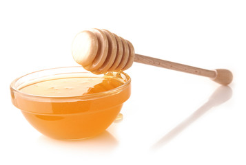 Honey pouring from drizzler into the bowl. Bowl is on a white
