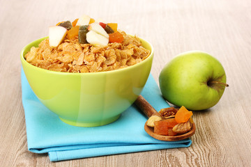 tasty cornflakes in bowl with dried fruits and apple