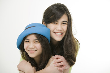 Two sisters or friends hugging each other, isolated on white