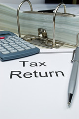 Tax return papers next to folder and calculator with copy space