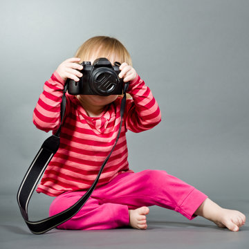 Cute little baby with digital photo camera