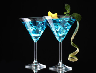 Blue cocktail in martini glasses on black background