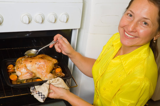 Woman Cooking  Chicken In Oven