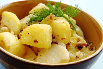 potatoes garnished with dill in a brown earthenware dish