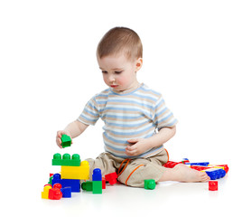 little cheerful child playing with construction set over white b
