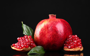 ripe pomegranate fruit with leaves on black background