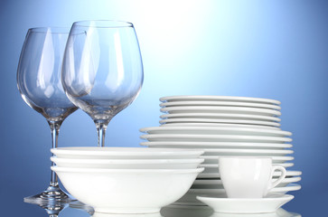 empty bowls, plates, cups and glasses on blue background
