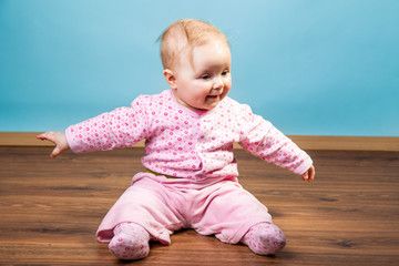 Infant girl playing in room on wooden floor