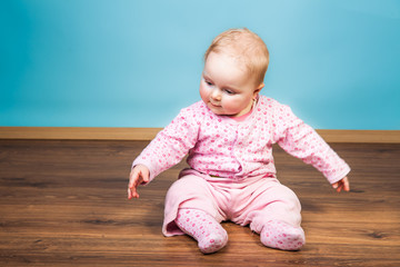 Infant girl playing in room on wooden floor