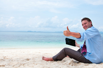 Fototapeta na wymiar Człowiek siedzi i pracy na plaży z tabletu kom
